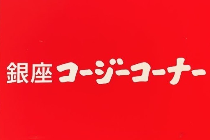 A sign on a brick wall with Japanese text that reads “銀座コージーコーナー” (Ginza Cozy Corner)