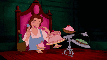 Belle enjoying various desserts at a table in a scene from "Beauty and the Beast".