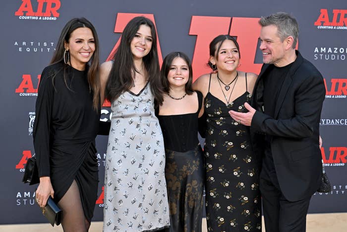 Matt Damon (wearing a black suit) and four women in various dresses smile together on the red carpet at an event for Amazon Studios' film "Air: Courting a Legend."