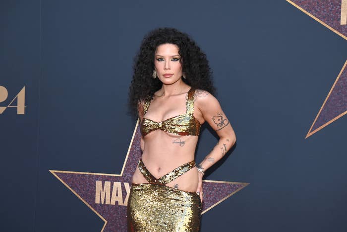 Halsey poses on the red carpet in a sequined gold ensemble featuring a bra top and long skirt at a celebrity event