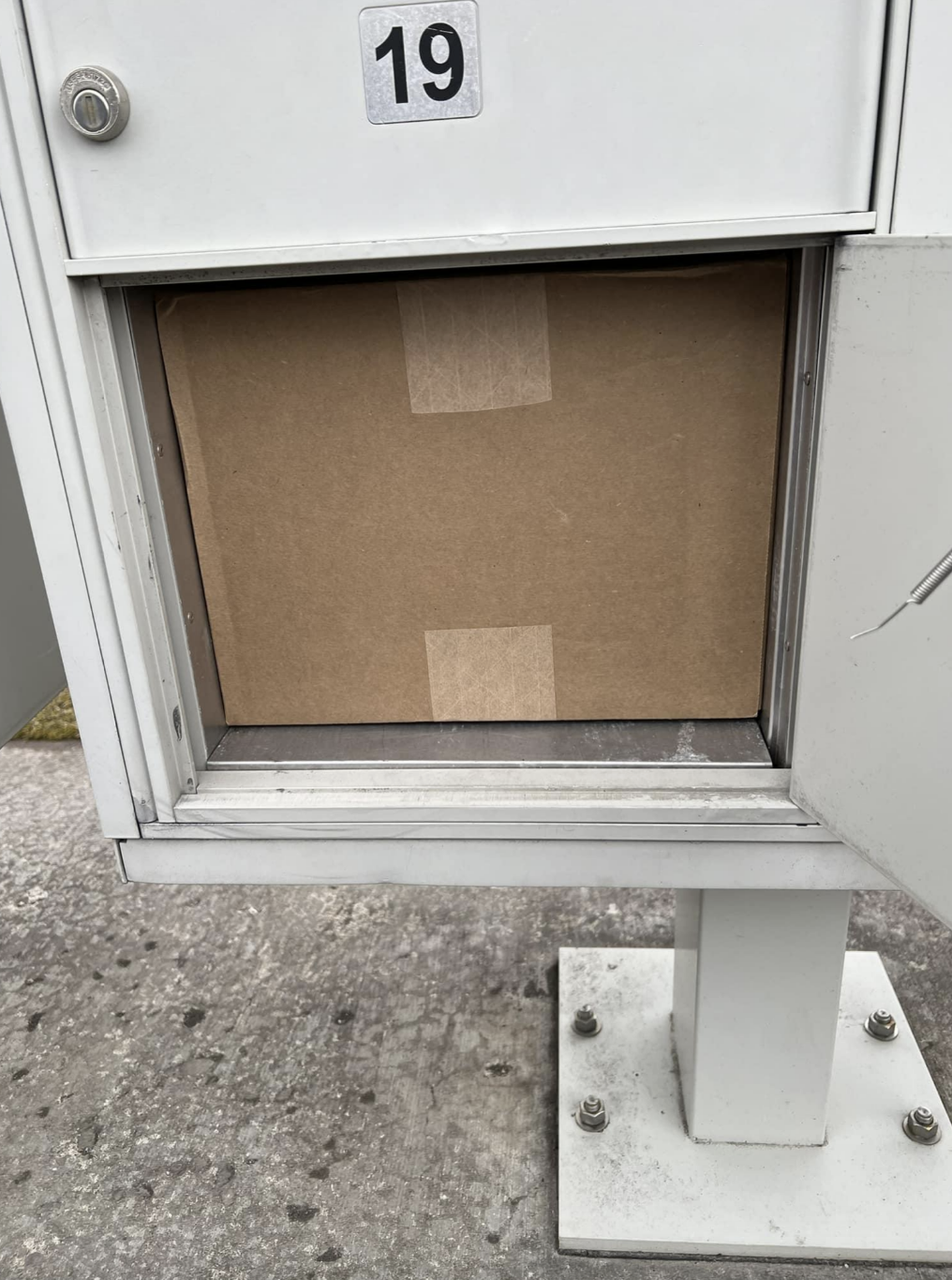 Mailbox #19 with an open door showing a cardboard package inside
