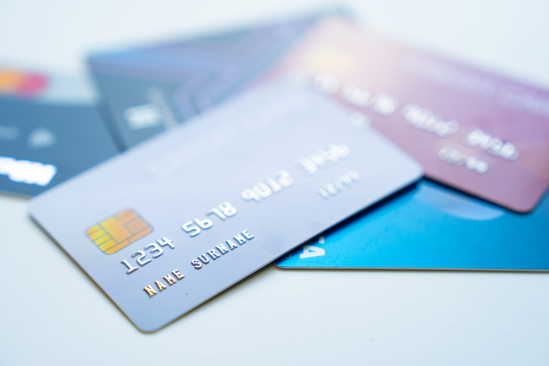Several credit cards are spread out on a surface, showing different card designs and the chip of a front card