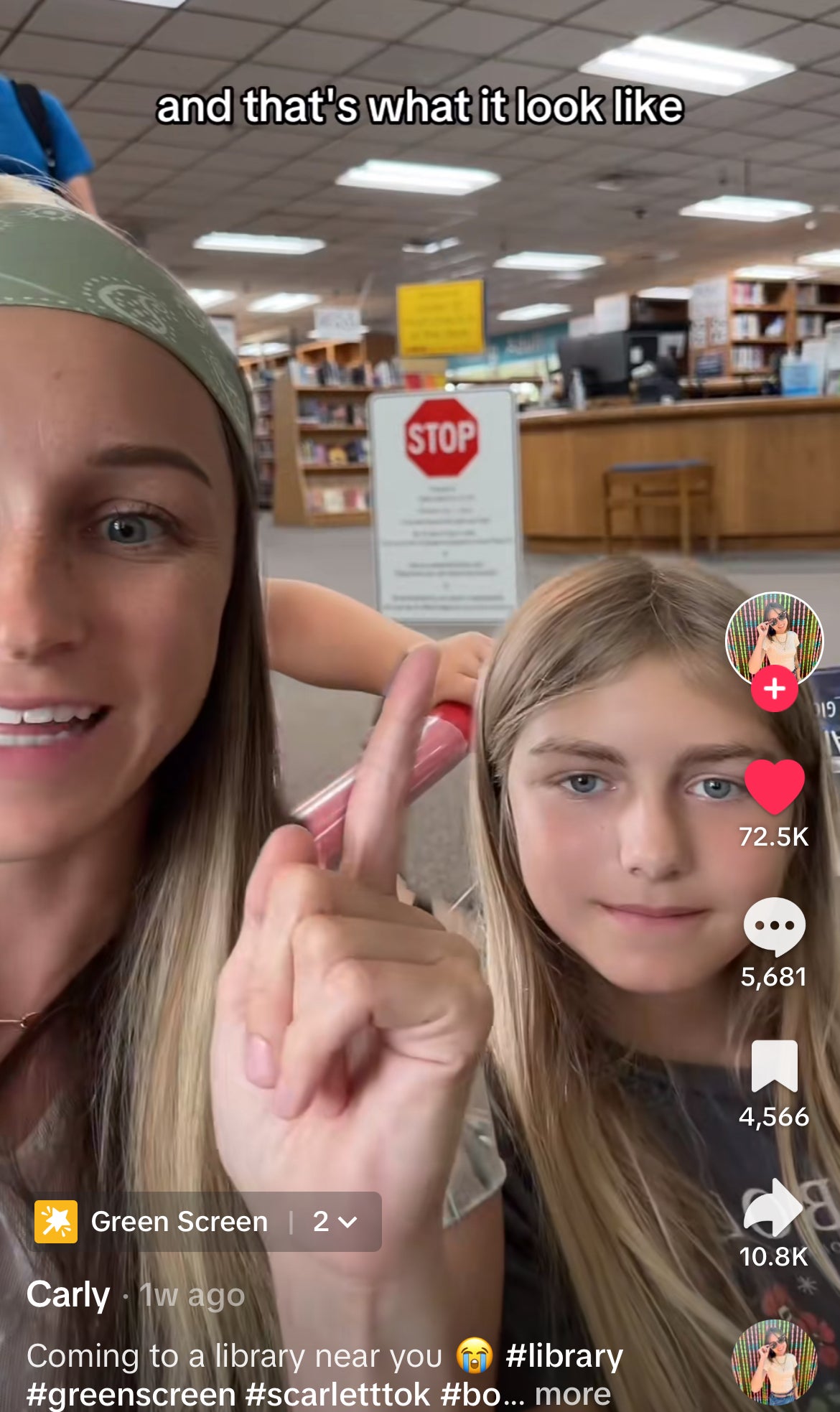 Carly and a young girl at the Idaho library, with a library sign in the background. Carly is pointing up