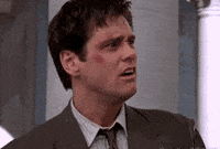 Jim Carrey, in a suit and tie, appears to be talking animatedly with a concerned expression on his face in a scene from a movie