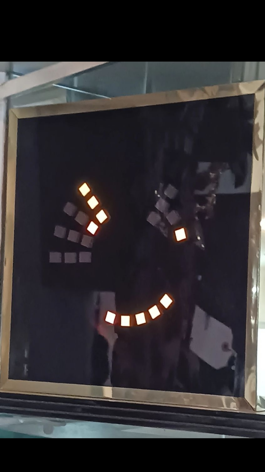 A digital art piece illuminated with small square lights arranged in a circle displayed in a gold frame