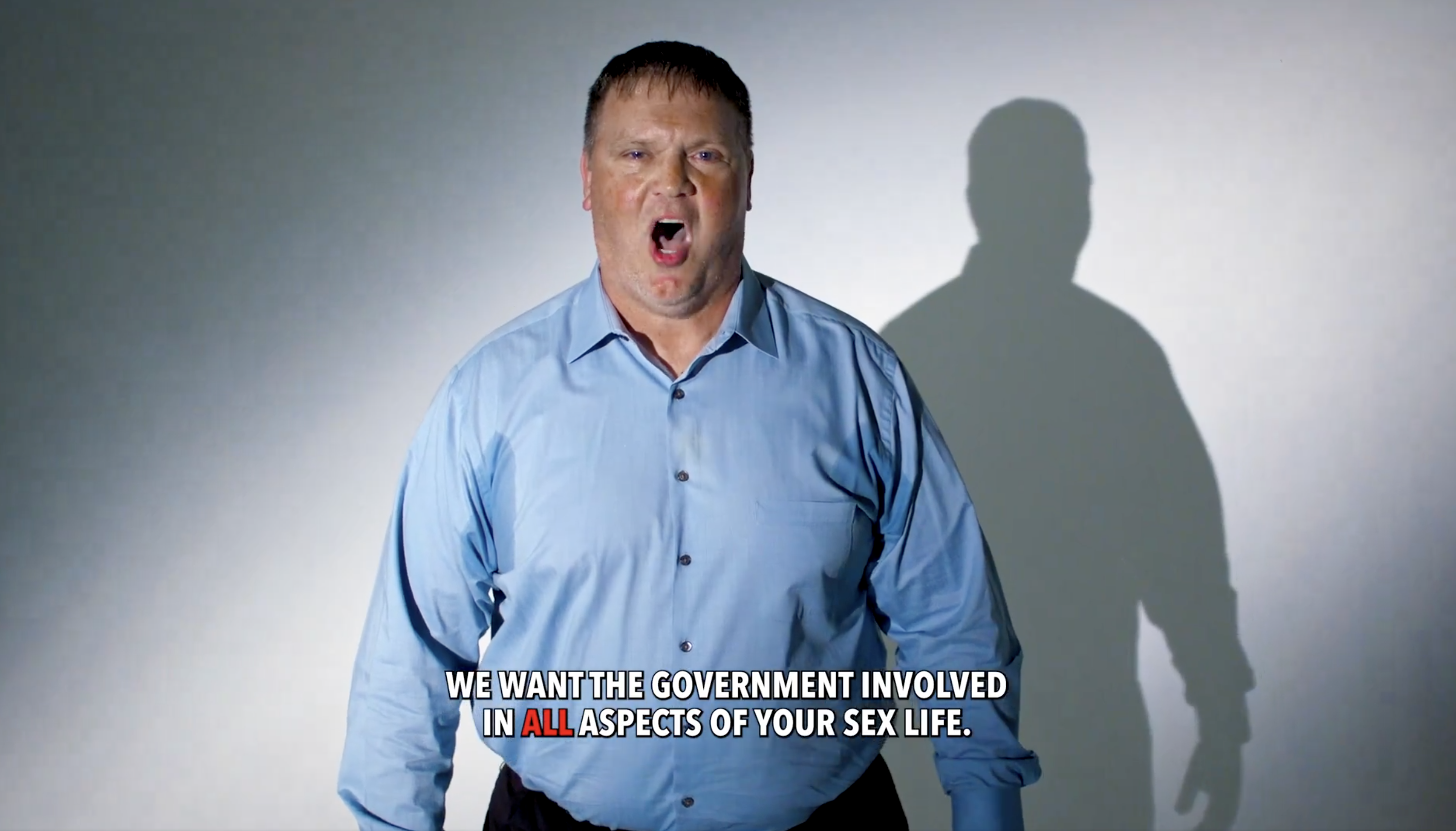 Middle-aged man wearing a light blue dress shirt, standing against a plain background; text below reads, "We want the government involved in all aspects of your sex life."