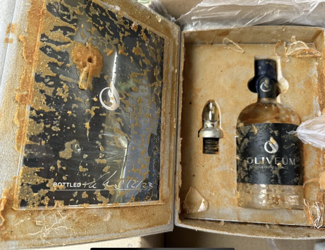 Weathered box with Olivum bottle and stopper; text "Bottled the Fall 2023" is on the left side inside the box