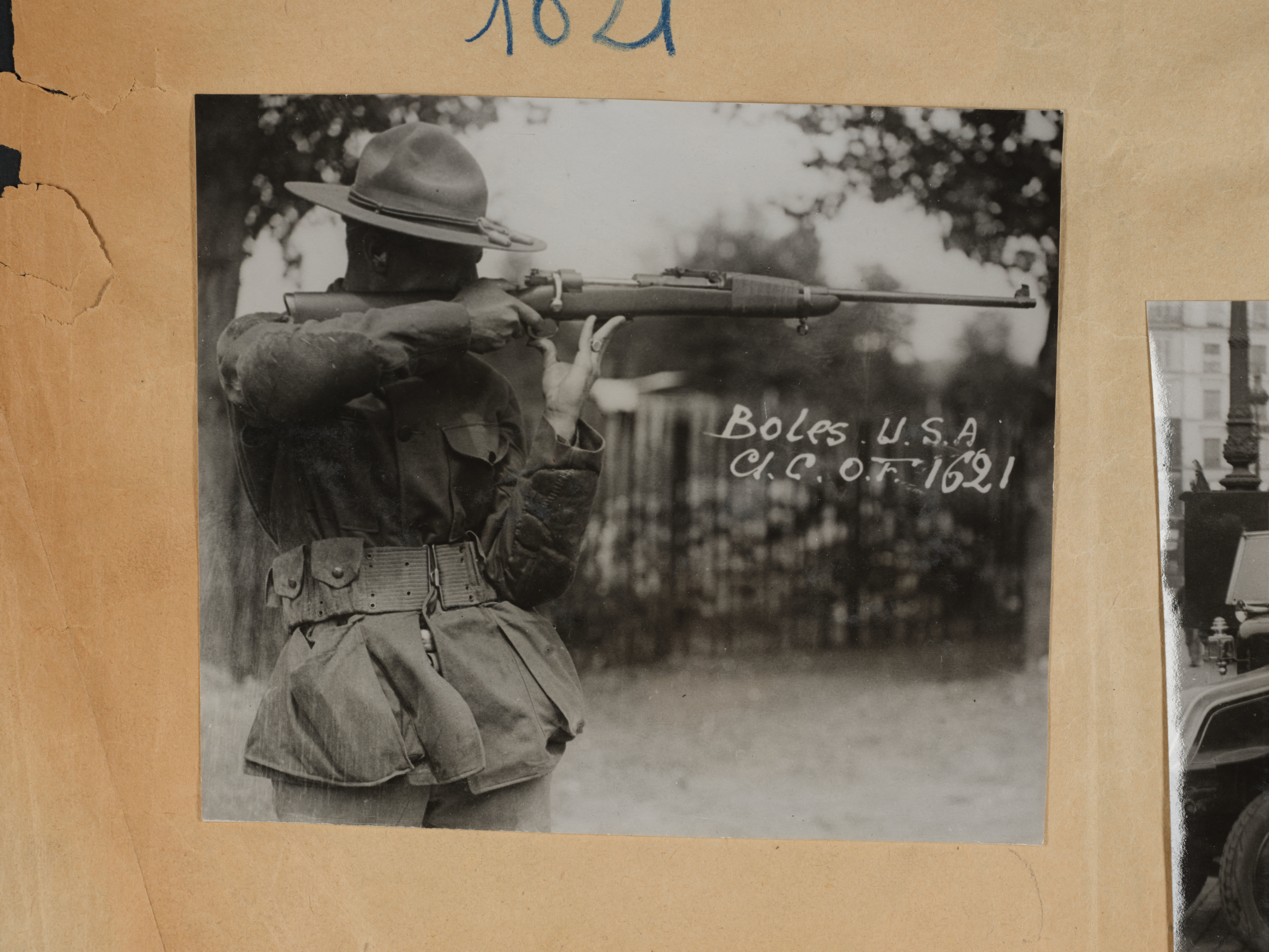 A vintage black-and-white photograph shows Boles, U.S.A., aiming a rifle outdoors, dated 1921. He is dressed in military uniform with a wide-brimmed hat