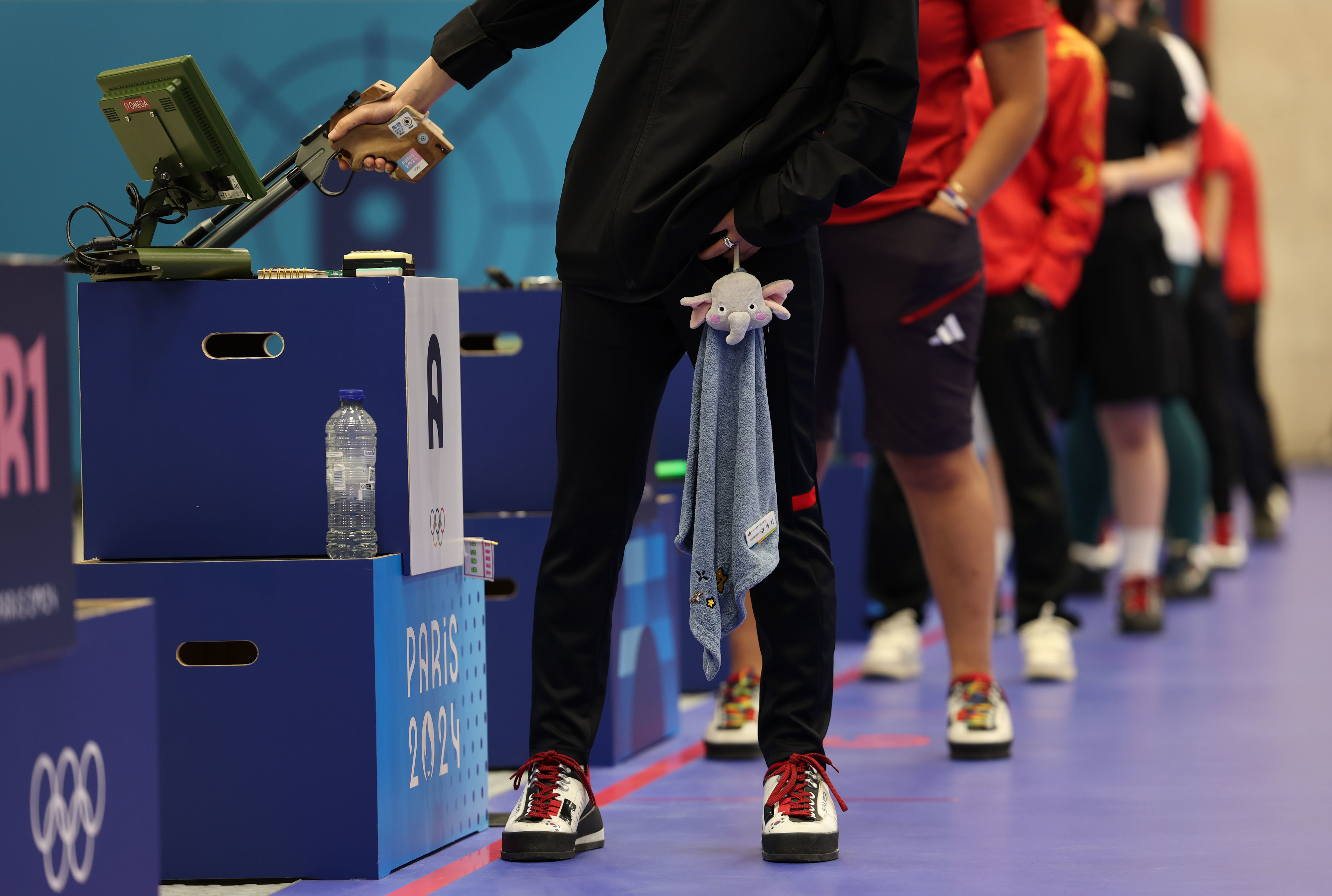 Athletes on the Tokyo 2020 Olympic shooting range, standing in line, holding guns