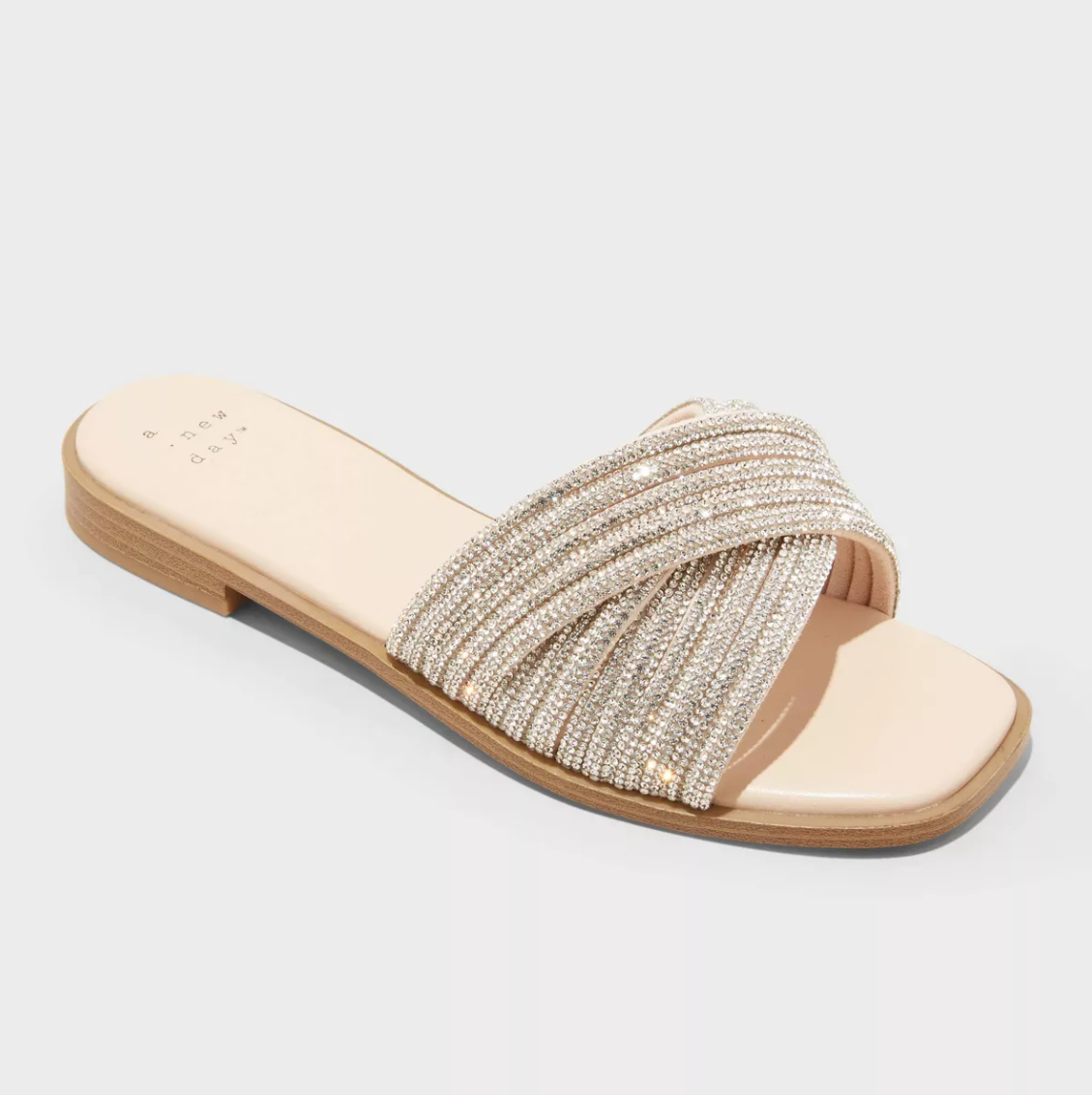 A beige sandal with a low wooden heel and a sparkly twisted strap design
