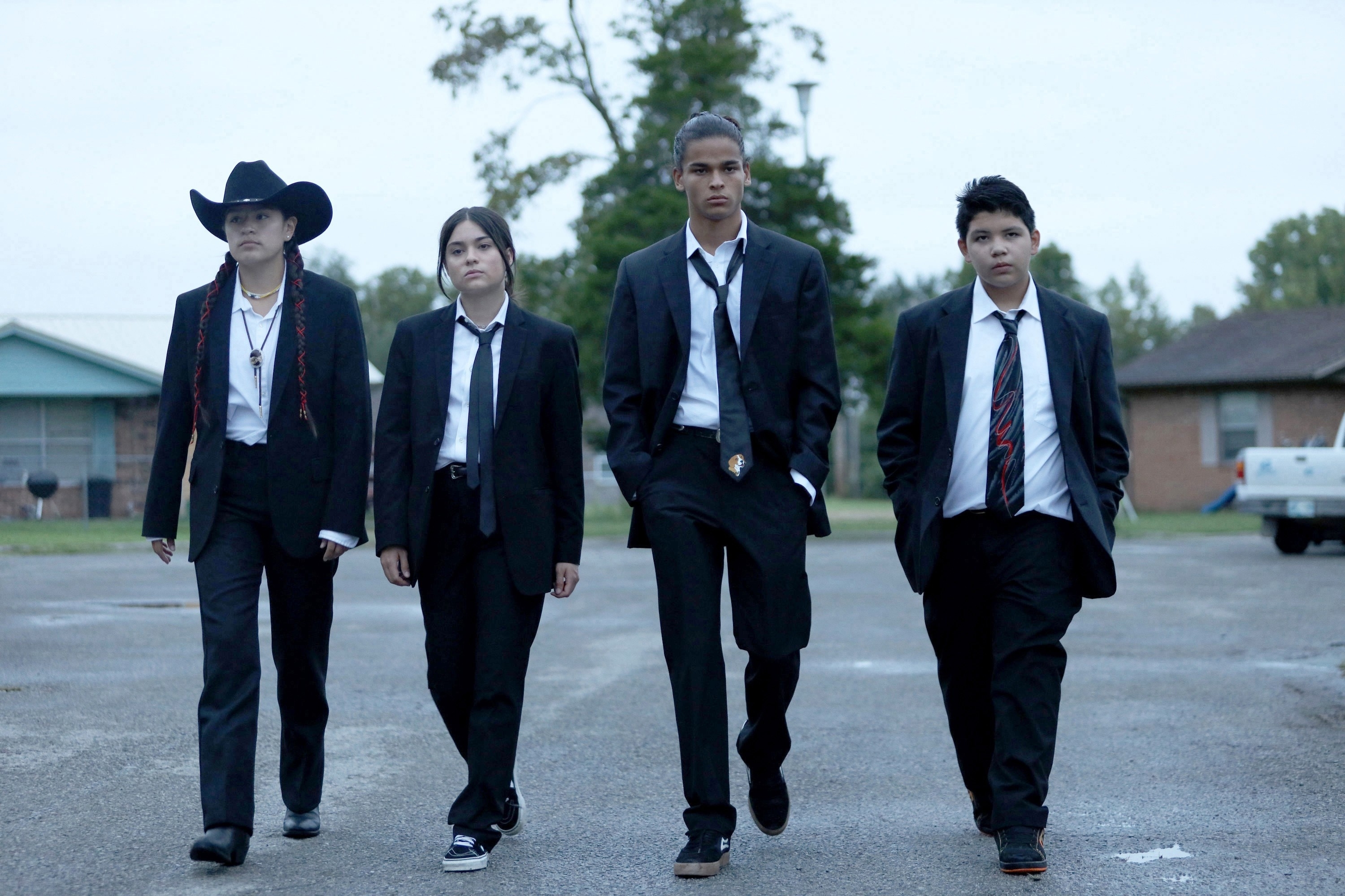 Paulina Alexis, Devery Jacobs, D'Pharaoh Woon-A-Tai, and Lane Factor walking in suits in a scene from "Reservation Dogs"
