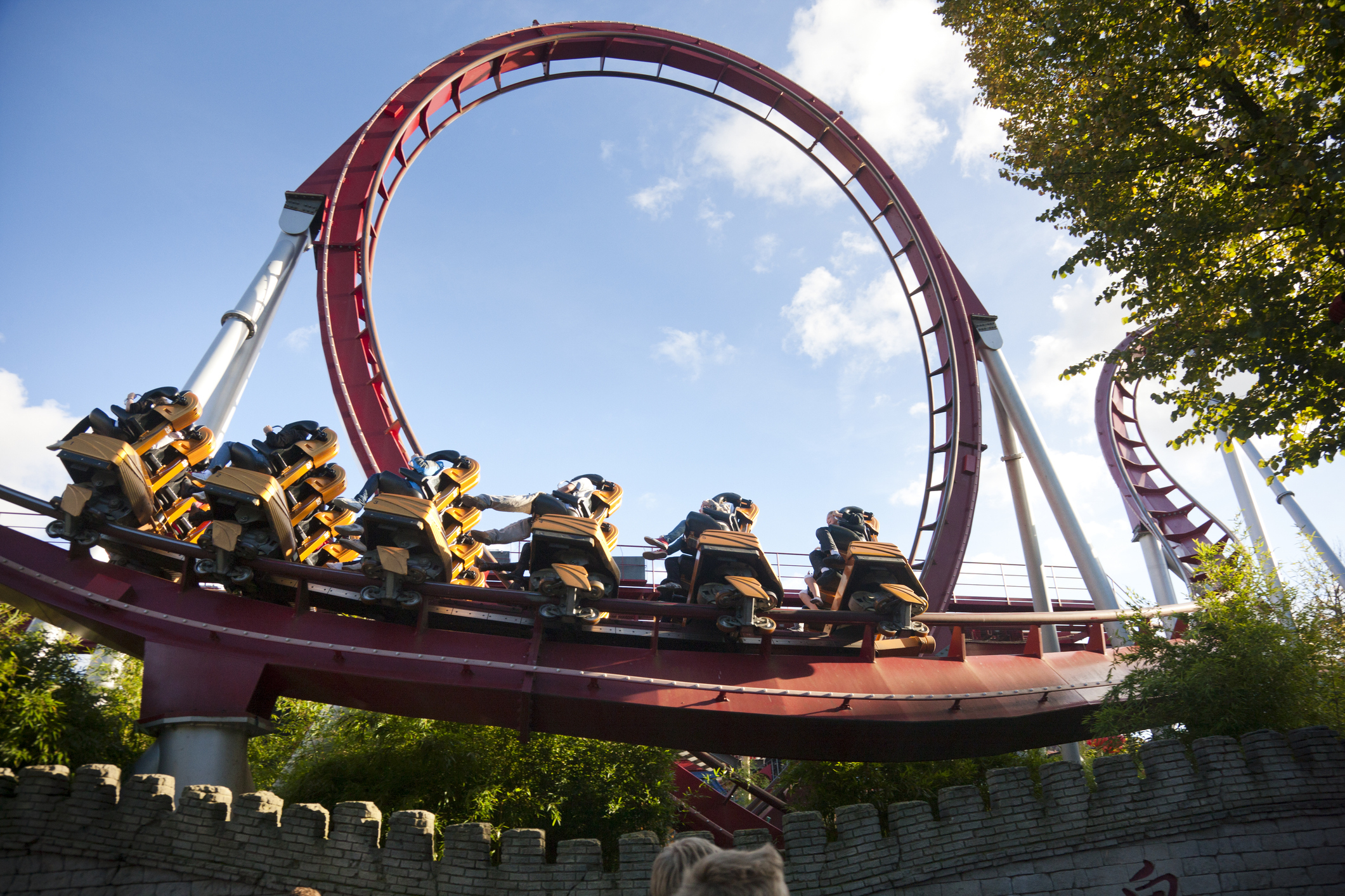 Roller coaster with people riding through a loop, clear blue sky, green trees in the background. The image is used in an article categorized as Internet Finds