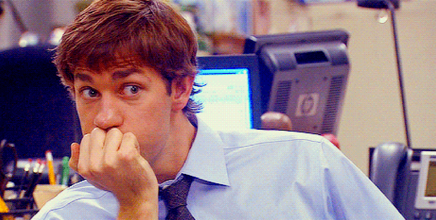 Jim Halpert from The Office is seated, wearing a light blue shirt and dark tie, with a neutral expression on his face
