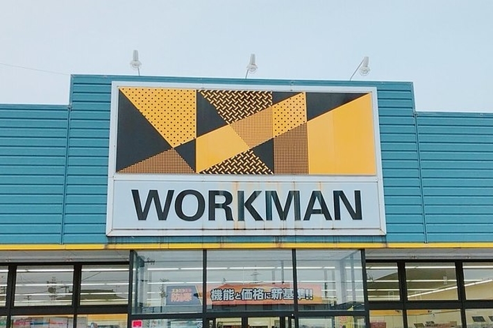 WORKMANストアのファサード。ジオメトリックパターンの看板とガラス扉の入り口が見える。