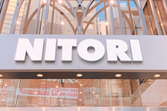 NITORIの店舗入り口。看板には「NITORI」と大きな文字で表示されています。背景にはビルの反射ガラスが見えます。