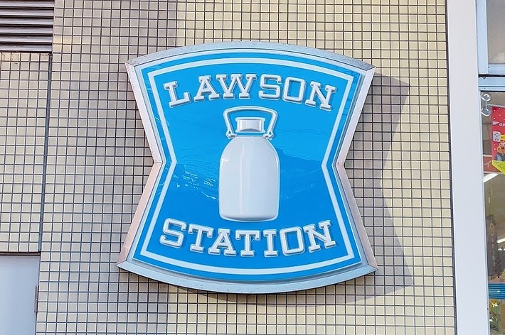ローソンの店舗看板。青い背景にミルク缶が描かれており、上部に「LAWSON」、下部に「STATION」と記載されている。