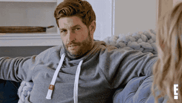 Jay Cutler sitting on a couch, wearing a hoodie, looking at Kristin Cavallari who is partly visible