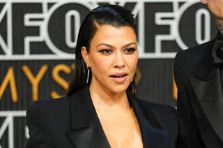 Kourtney Kardashian on the red carpet wearing a sleek black blazer and drop earrings, attending a celebrity event