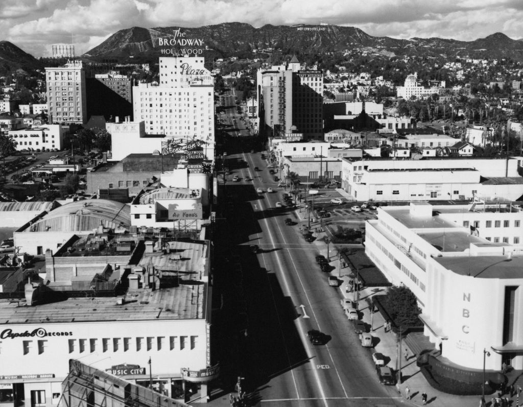 A historical aerial view of Hollywood, featuring visible landmarks such as the Broadway Hollywood Building and the Hollywood sign in the background