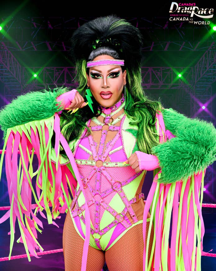 A drag performer from Canada's Drag Race in a vibrant, neon-themed outfit with fringe details and dramatic makeup poses confidently in a wrestling ring backdrop