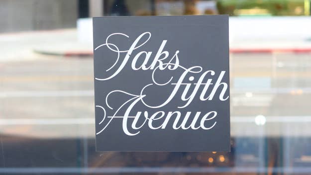 Saks Fifth Avenue store sign with elegant white cursive text displayed on a dark background