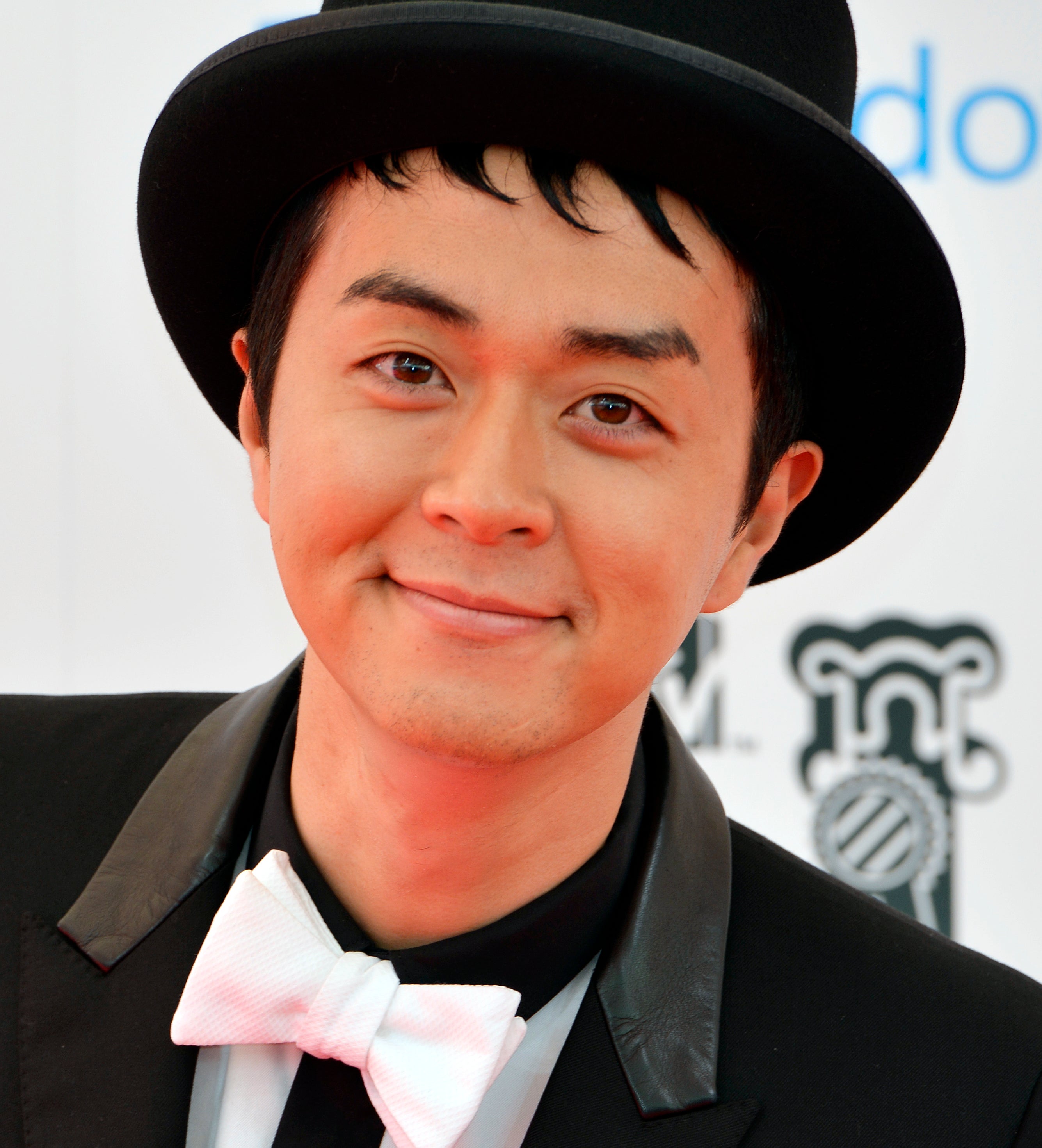 黒木啓司、黒いスーツとシルクハット、白い蝶ネクタイを身に着け、赤いカーペットに登場。