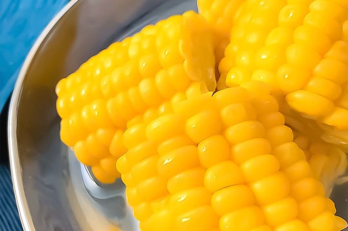 料理皿に盛られたトウモロコシの切り株が3つ、湯で調理された箇所が鮮やかに写っています。