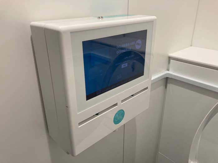 トイレの壁に取り付けられた、タッチスクリーン付きの白い操作パネル。