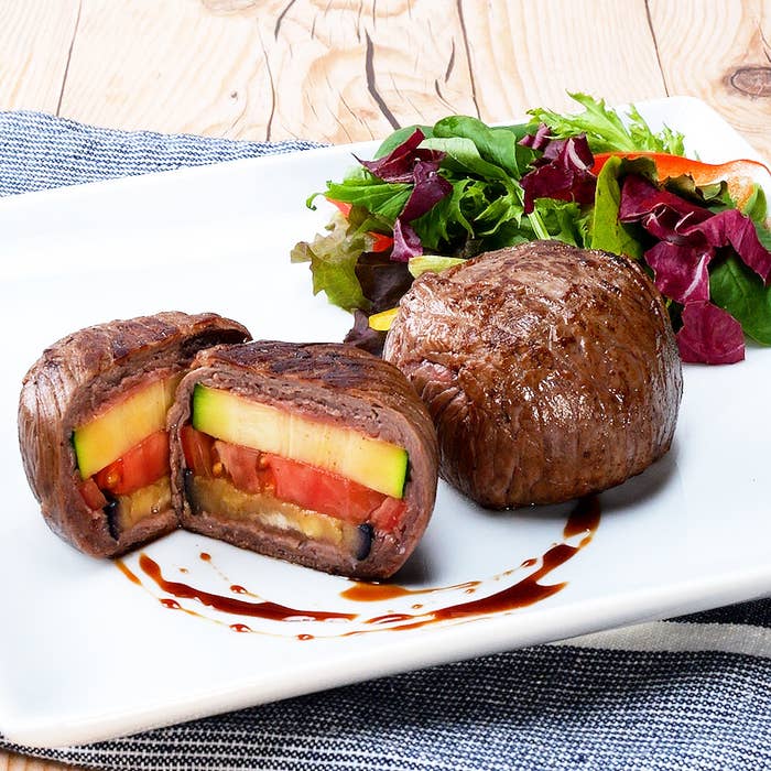 皿に盛られたカットされた肉料理。中にはトマト、ズッキーニなどの野菜が詰まっている。サラダ付き。