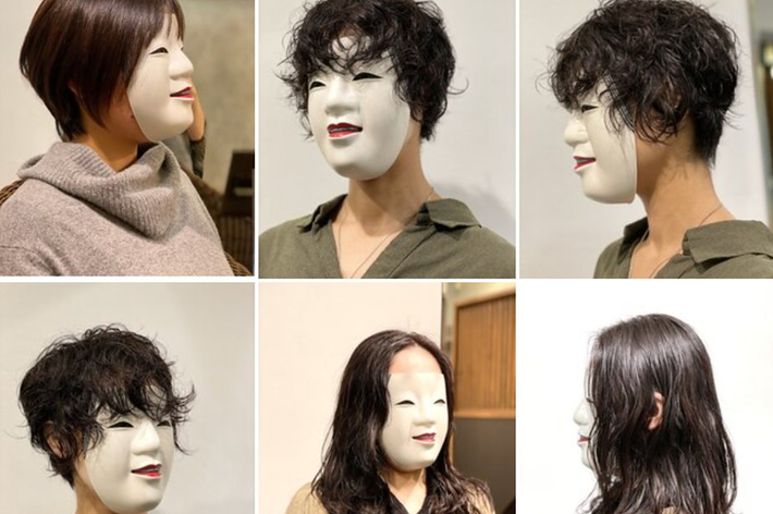 短い髪の女性が白い仮面をかぶり、シンプルなロングスリーブドレスを着ています。