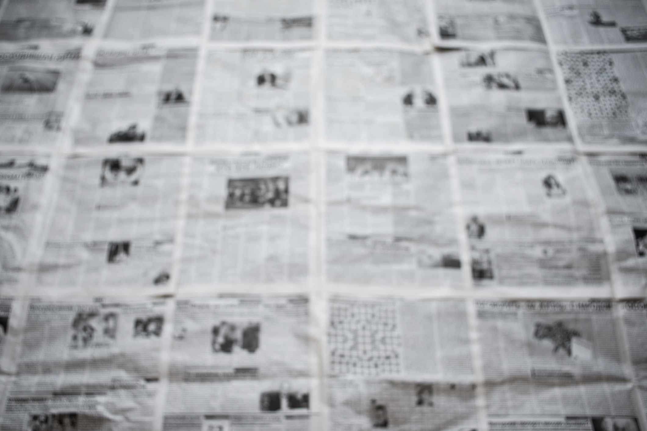 A large, blurry newspaper layout with numerous articles and images, making the specific content indistinguishable