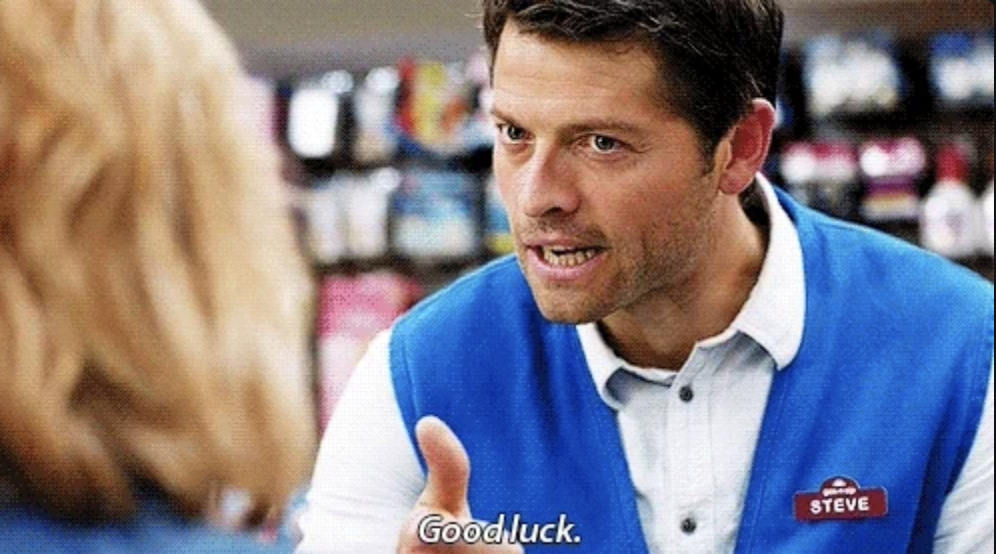 Misha Collins, wearing a blue vest with a "Steve" name tag, is shown speaking and giving a thumbs up. The text "Good luck." appears at the bottom