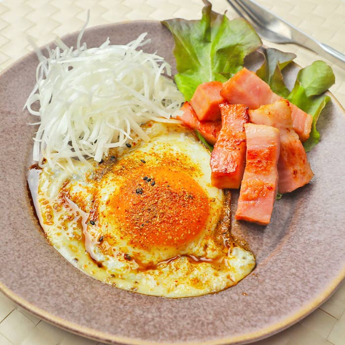 お皿には目玉焼き、角切りベーコン、生野菜が盛り付けられています。