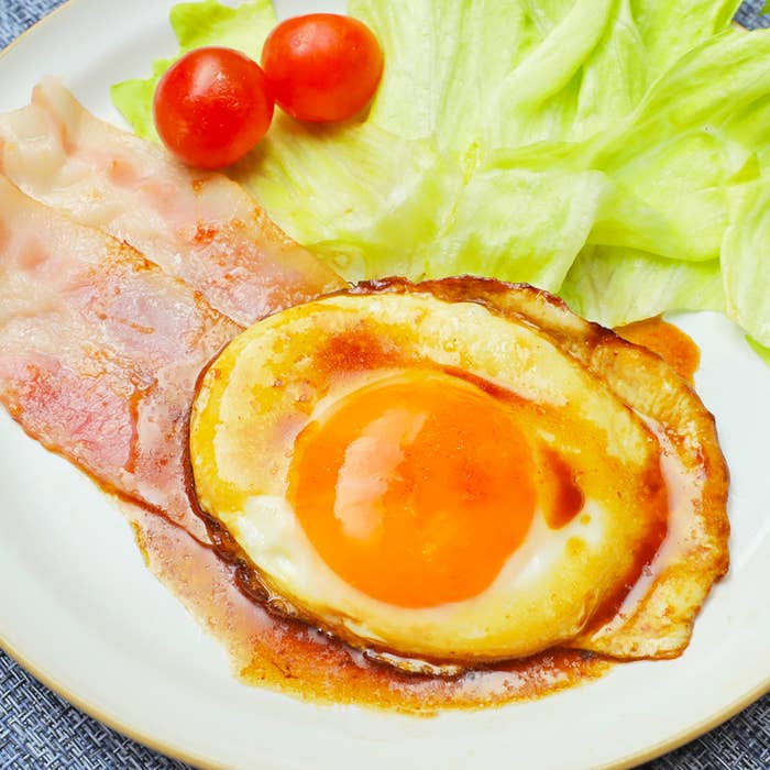 目玉焼き、ベーコン、レタス、ミニトマトが盛られたプレートの食事
