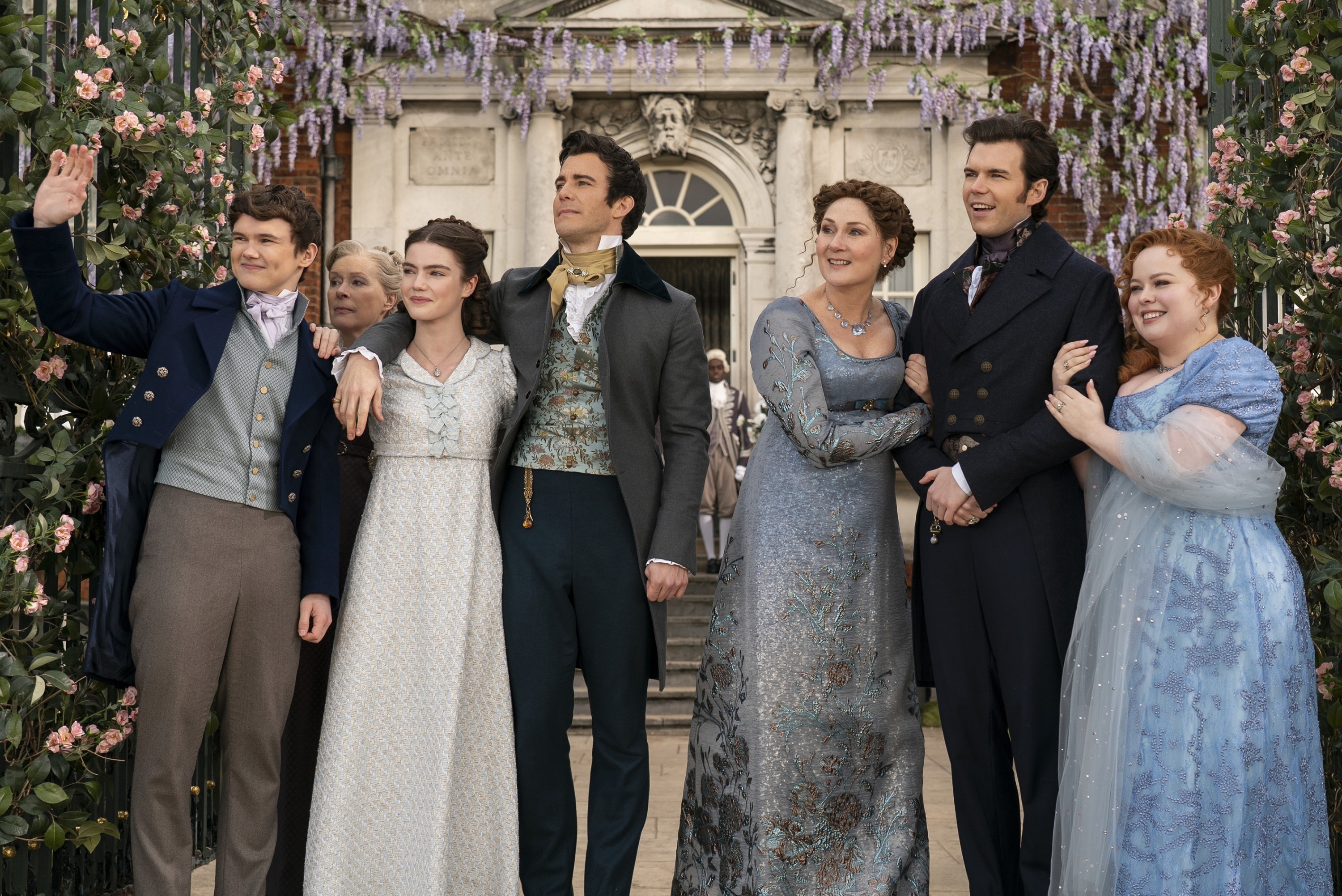 The image shows six characters from the show "Bridgerton" in Regency-era attire, standing outside a mansion with floral decorations. They are dressed in elegant period costumes