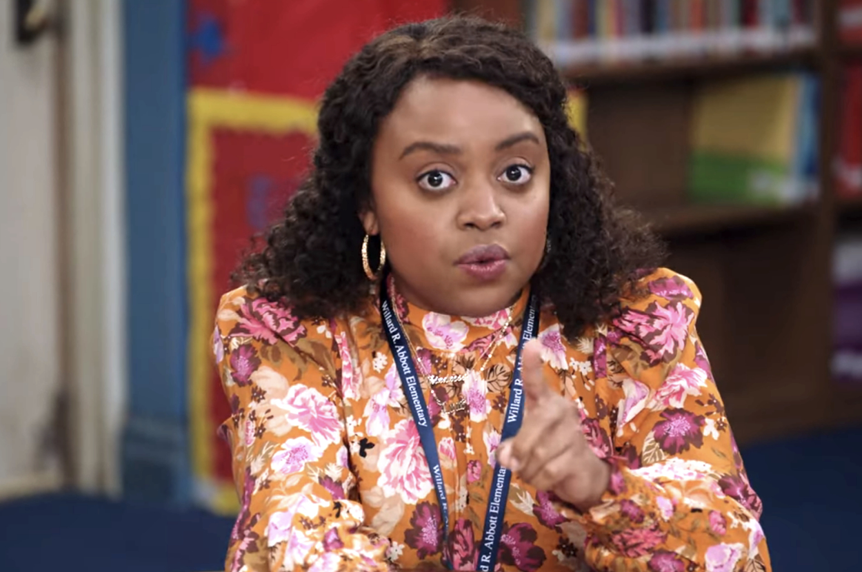 Quinta Brunson in a floral blouse, seated with a library backdrop from the TV show 