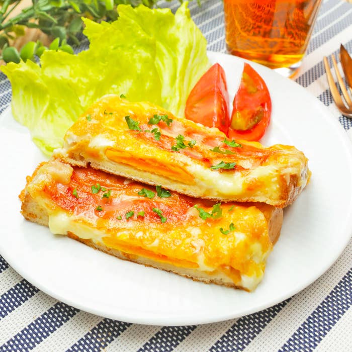 皿に盛られたレタス、トマト、そしてチーズトーストの朝食。