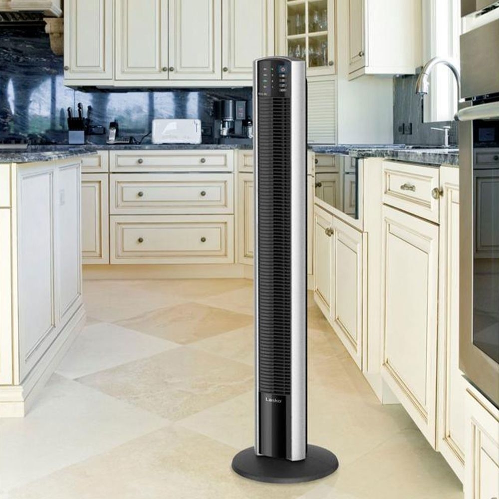 A tower fan placed in a modern kitchen with white cabinets and a marble countertop
