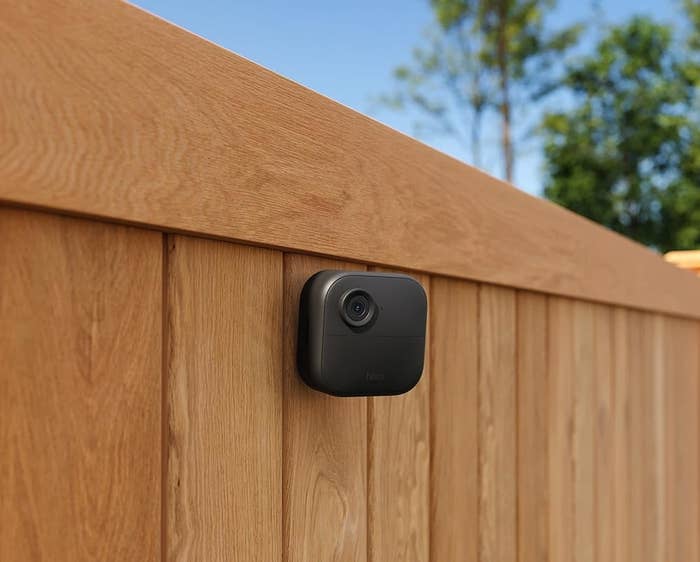 Security camera mounted connected a woody fence,