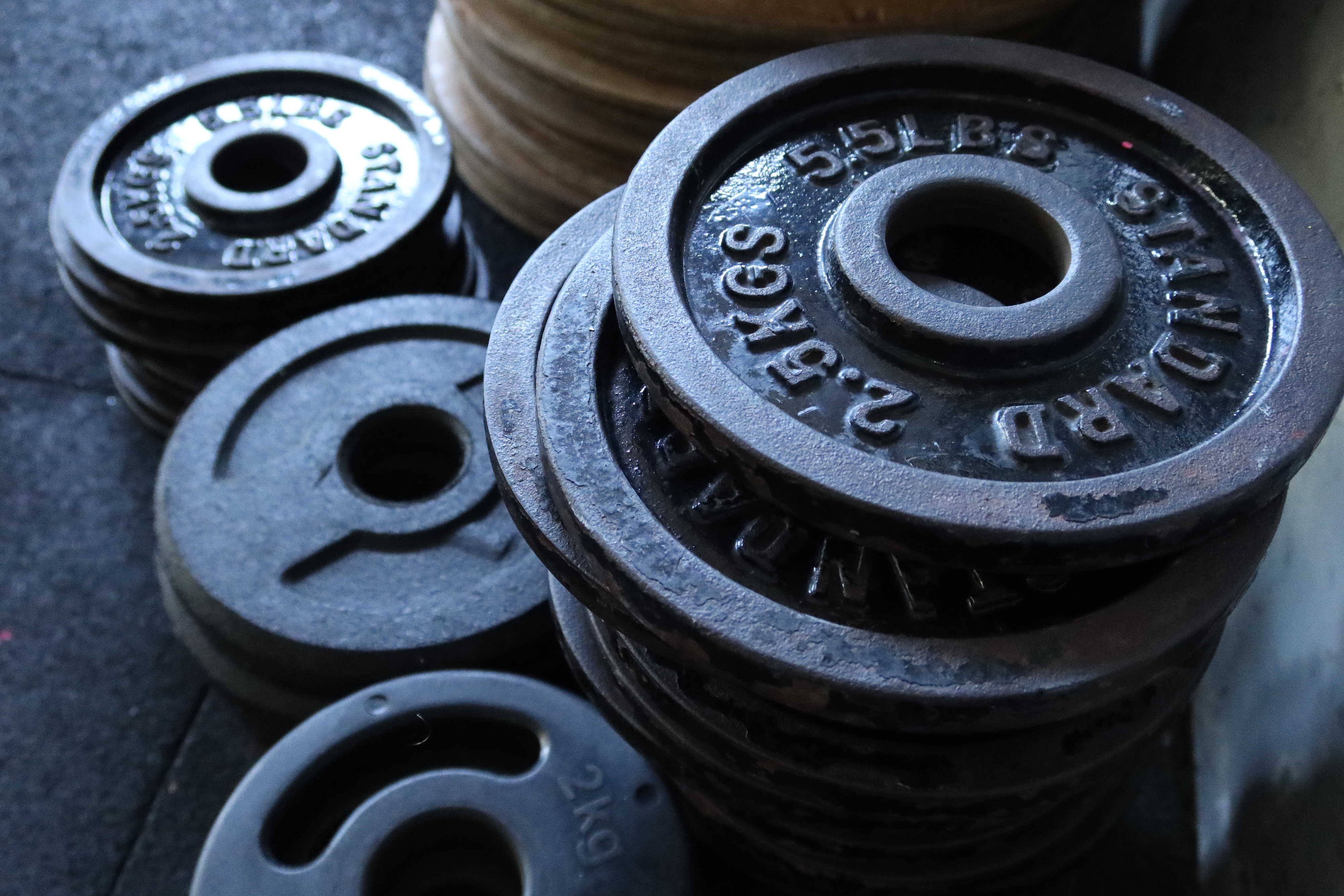 Stacks of standard weight plates of various sizes on a gym floor