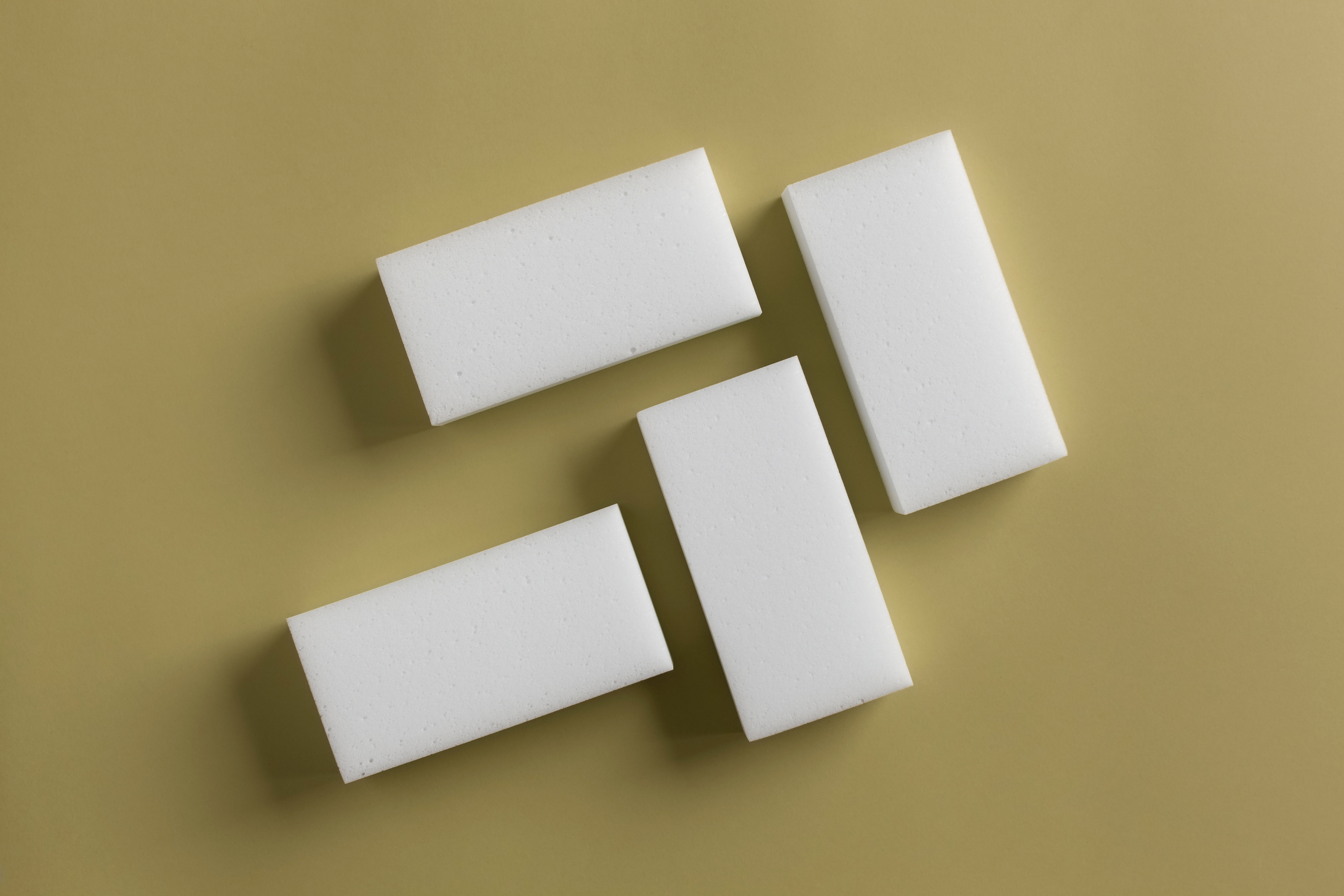 Four white rectangular erasers are arranged on a solid background