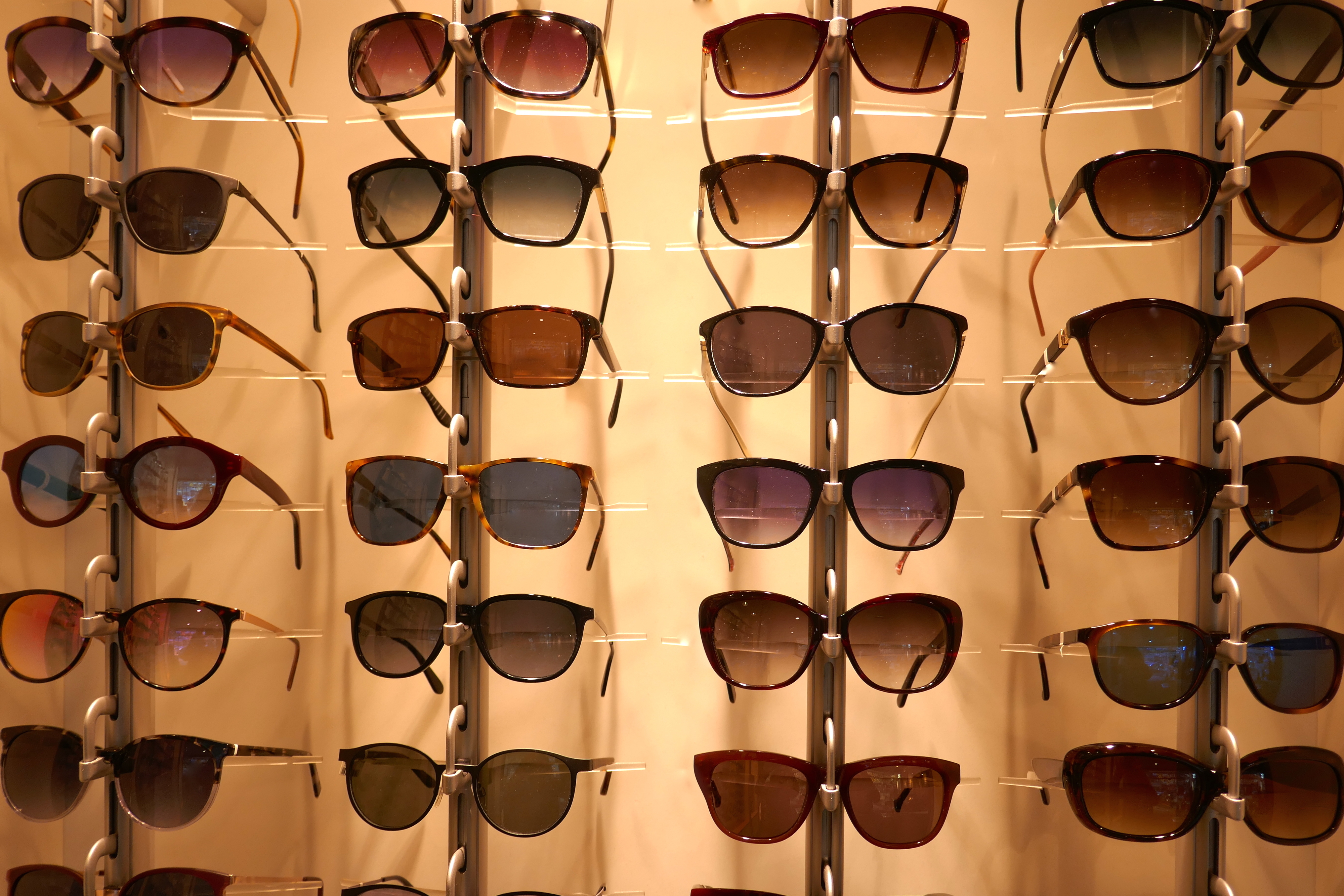 A display rack on a wall featuring various styles and designs of sunglasses