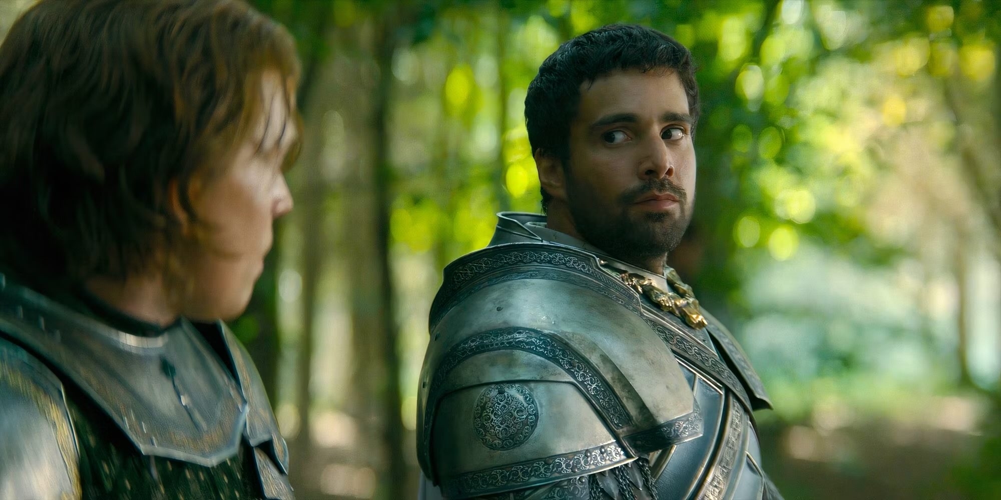 Paddy Considine y Fabien Frankel, vestidos con armaduras medievales, se miran en un bosque en una escena de una película o serie