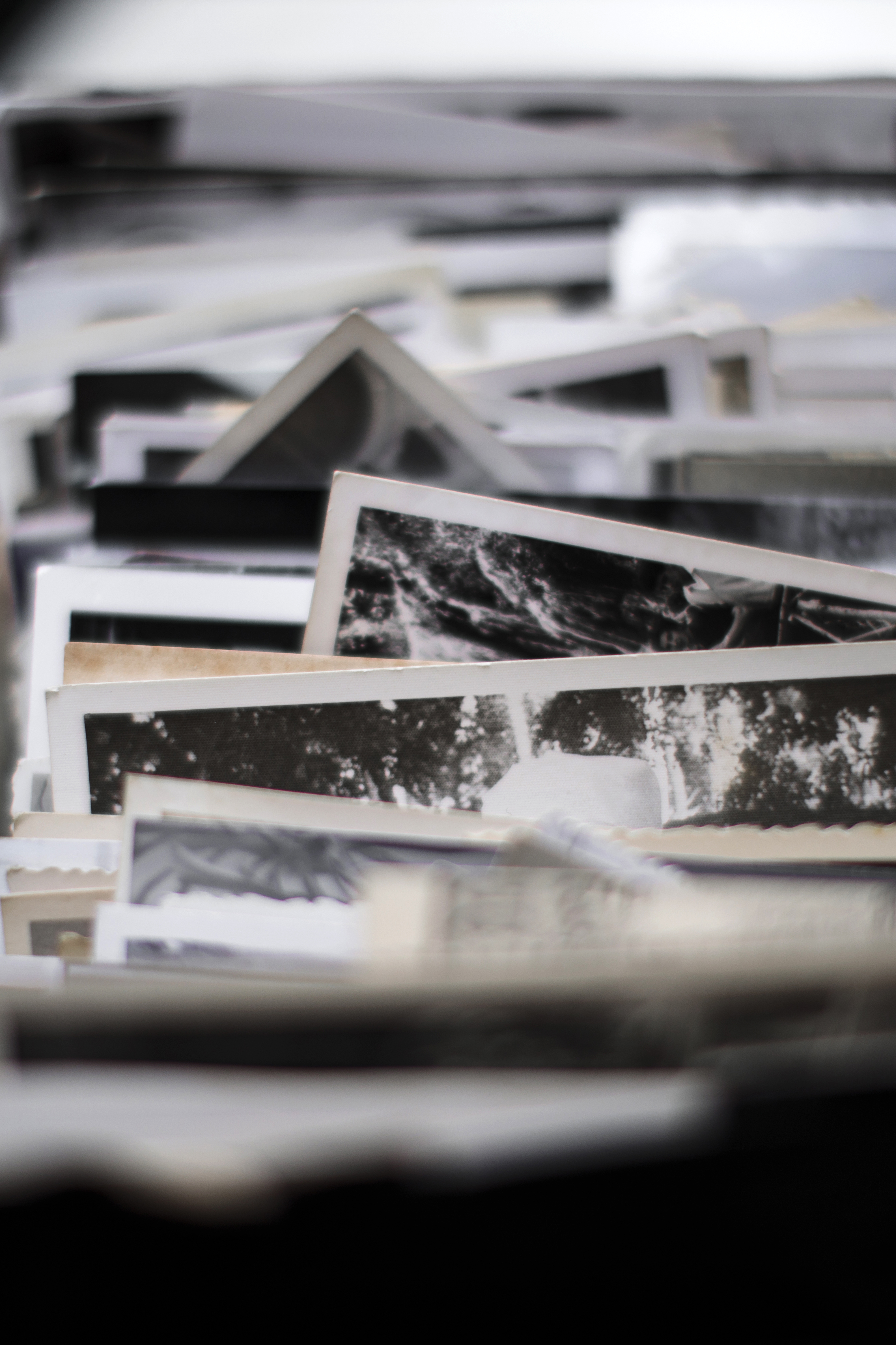 A cluttered pile of assorted vintage black-and-white photographs, some overlapping slightly, and containing various scenes and portraits.