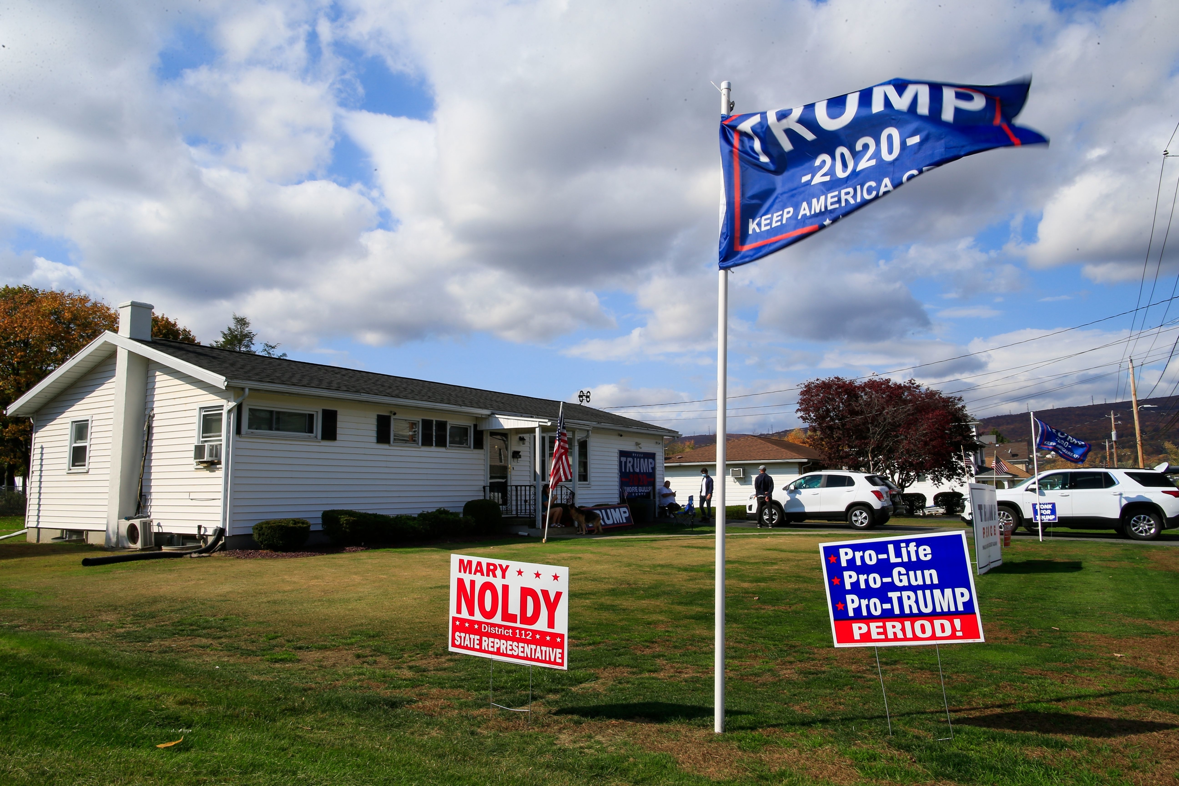 Lawn with Trump 2020 flags and signs supporting Mary Noldy for state representative, and pro-life, pro-gun, pro-Trump stances. House with an American flag in background