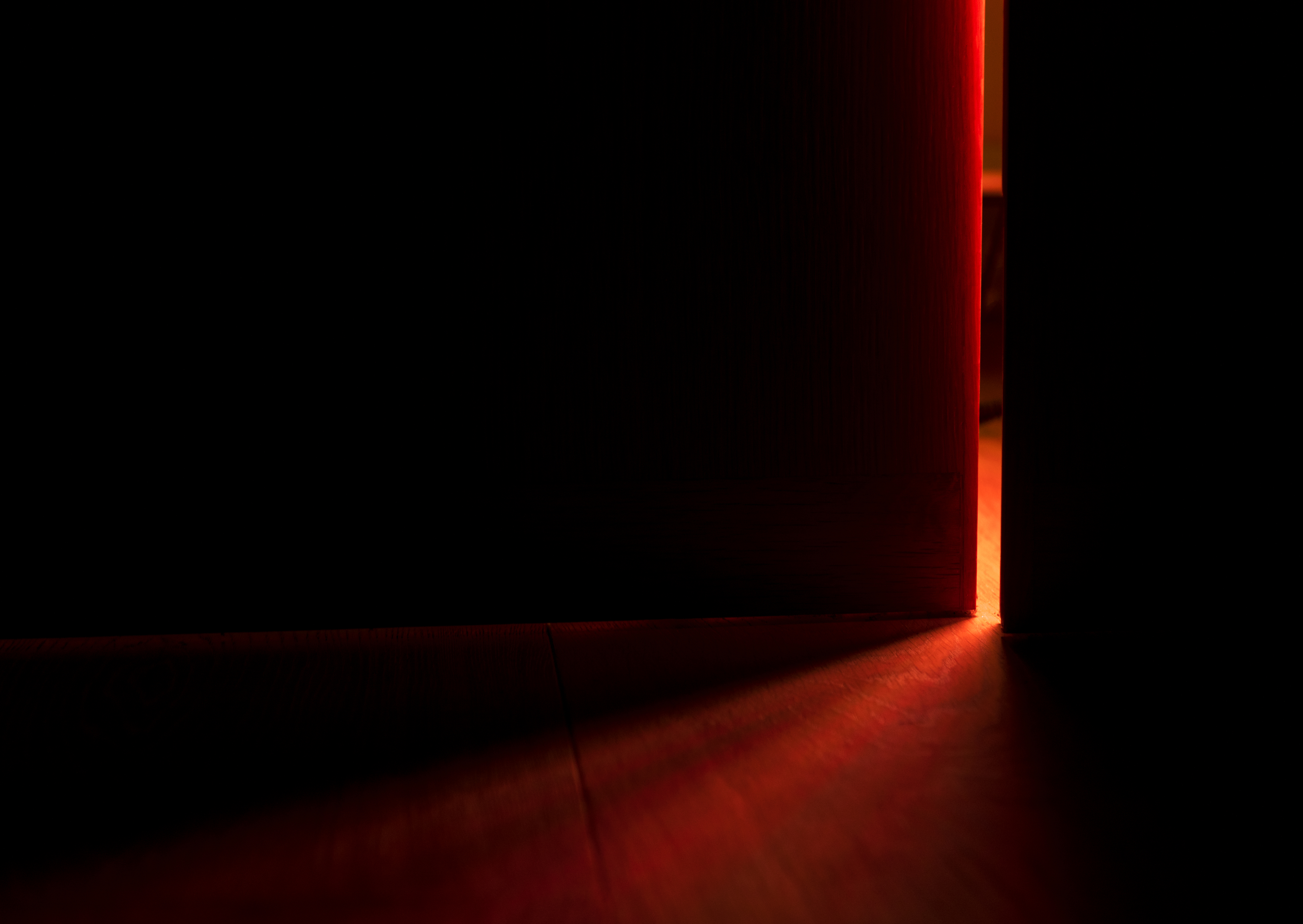 Partially open door casting light into a dark room