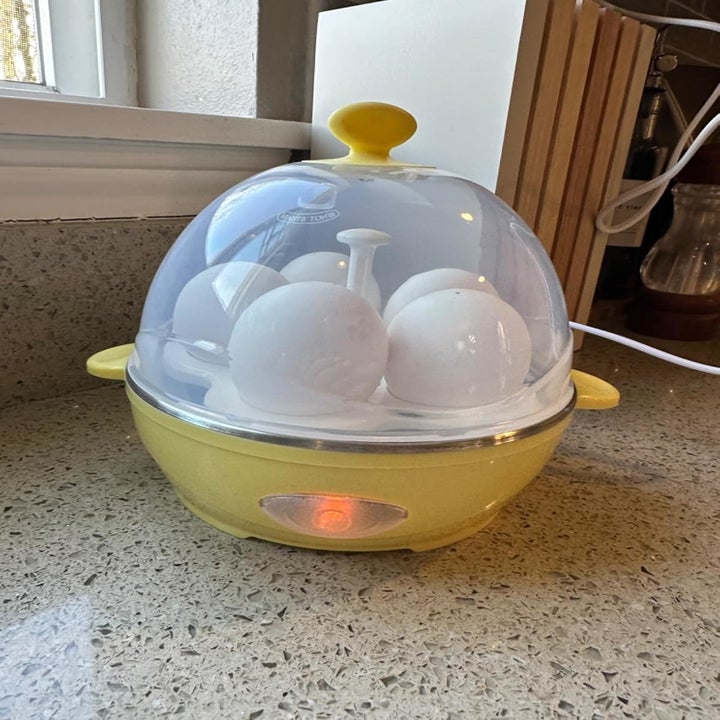 Electric egg cooker on a kitchen counter, boiling multiple eggs under a transparent lid