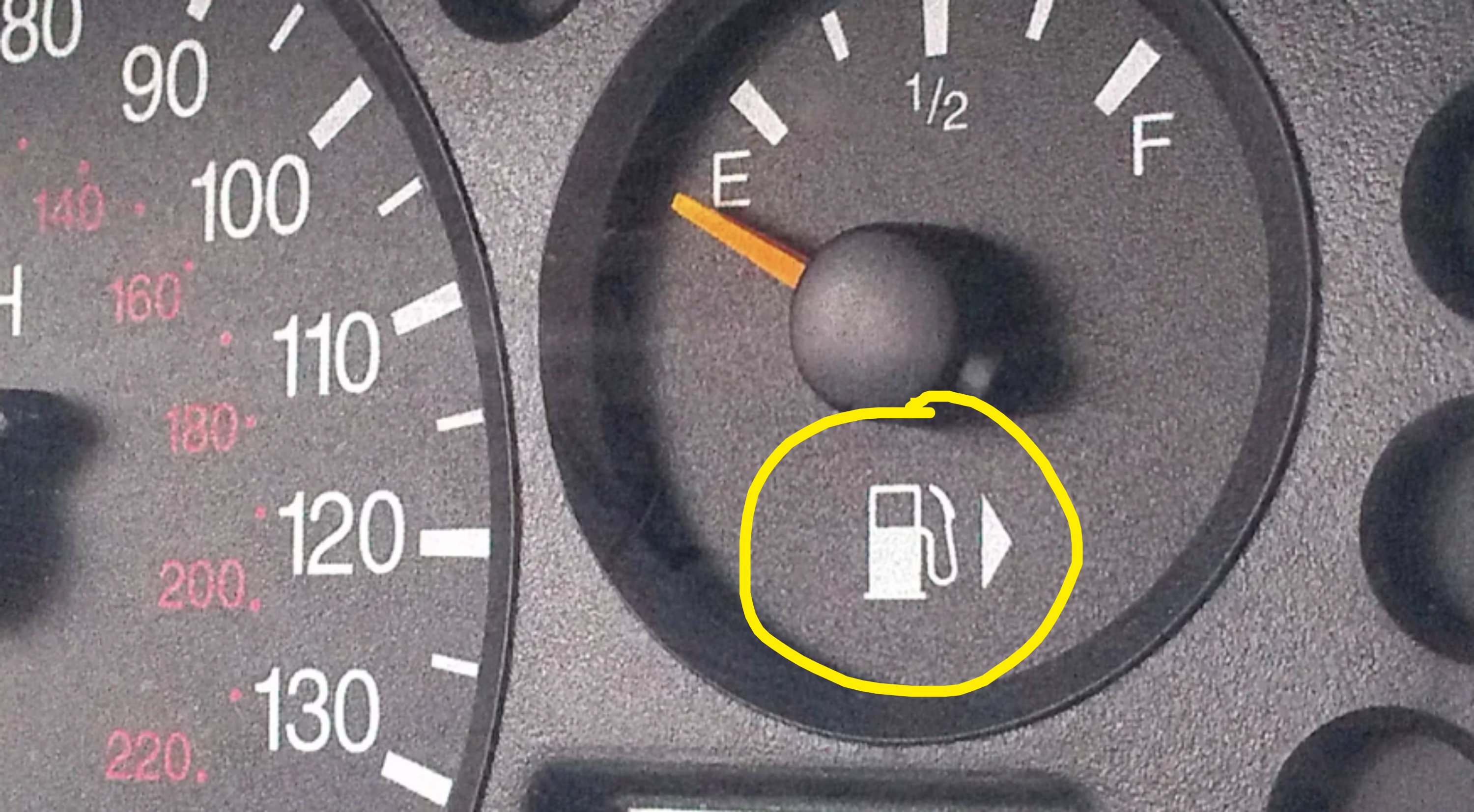 Car dashboard showing a fuel gauge with the needle on empty and a speedometer