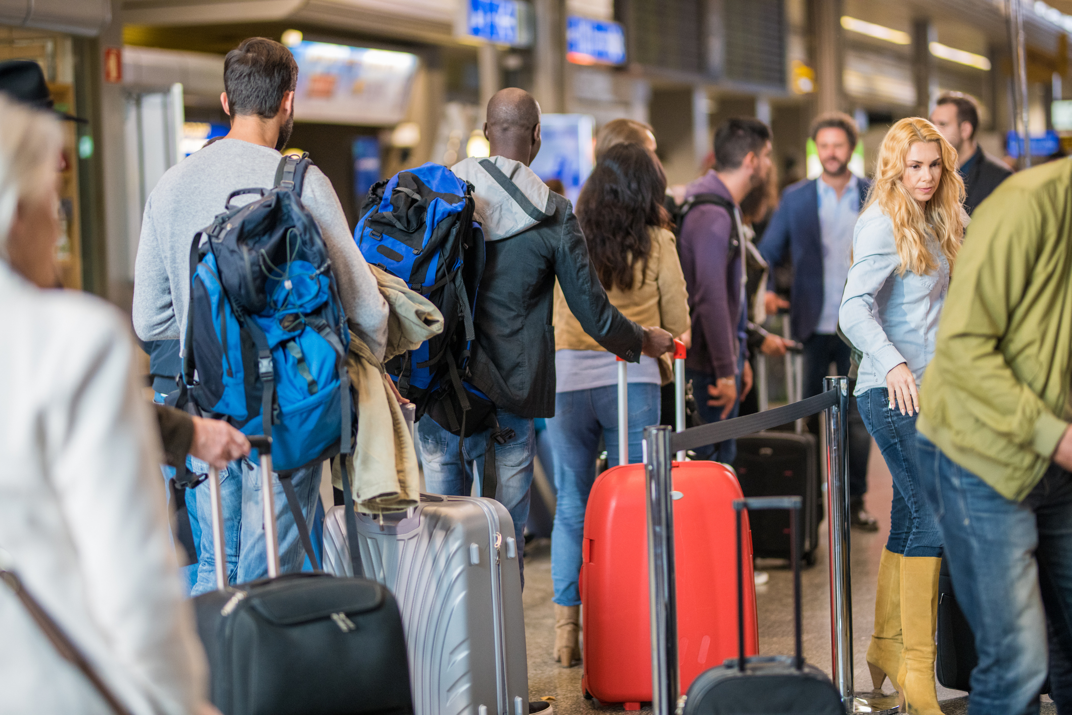Travelers with luggage standing in line at an airport check-in desk