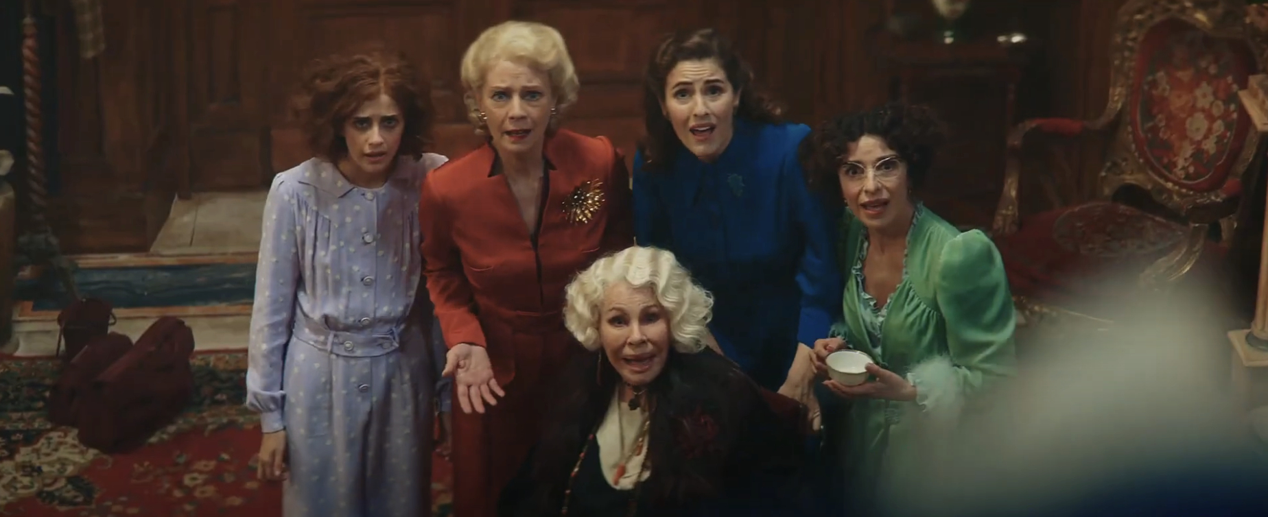 Women in period-style dresses looking surprised in a scene from a movie
